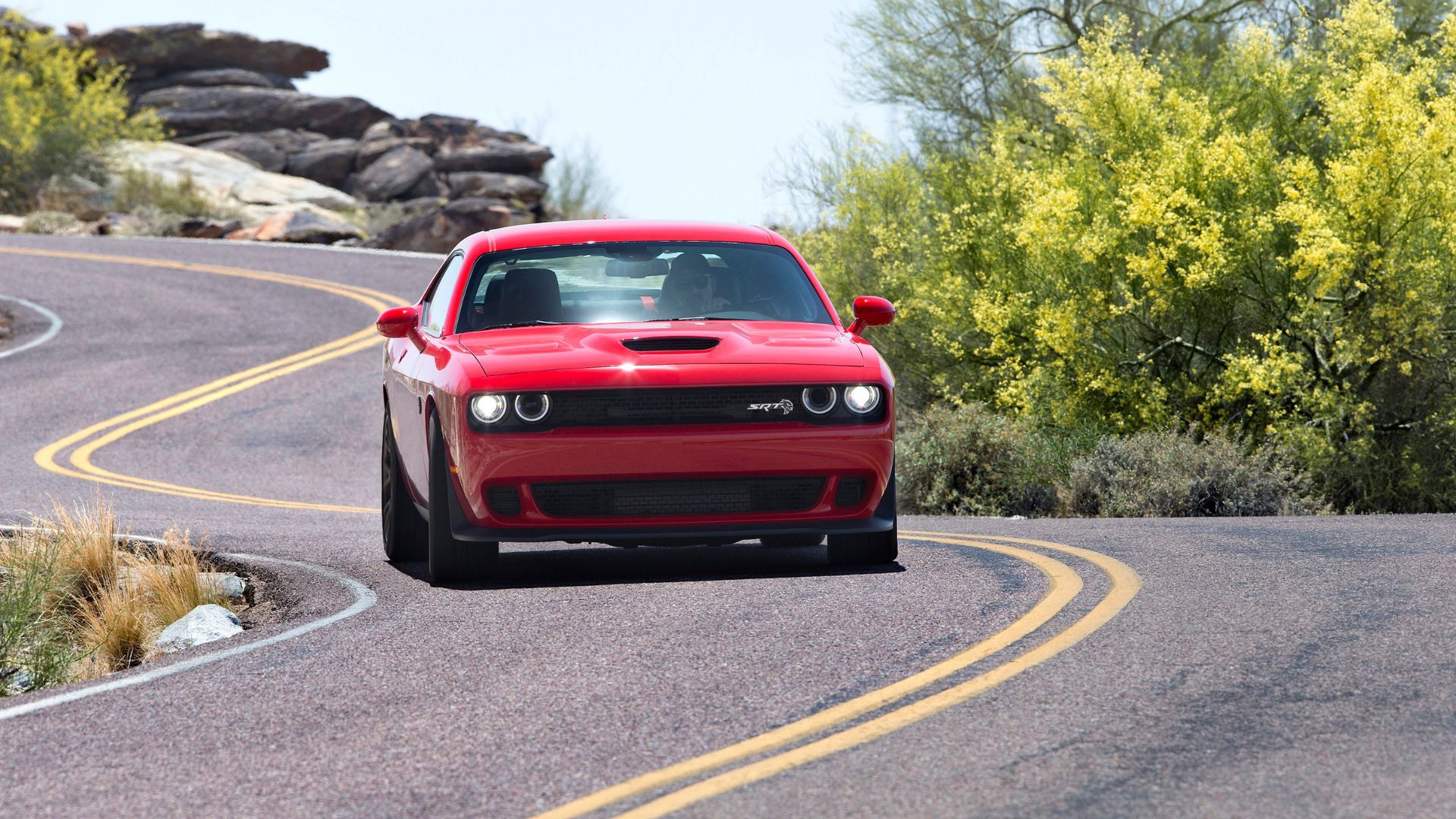 Red 2018 Dodge Challenger SRT Hellcat driving on a winding country road.