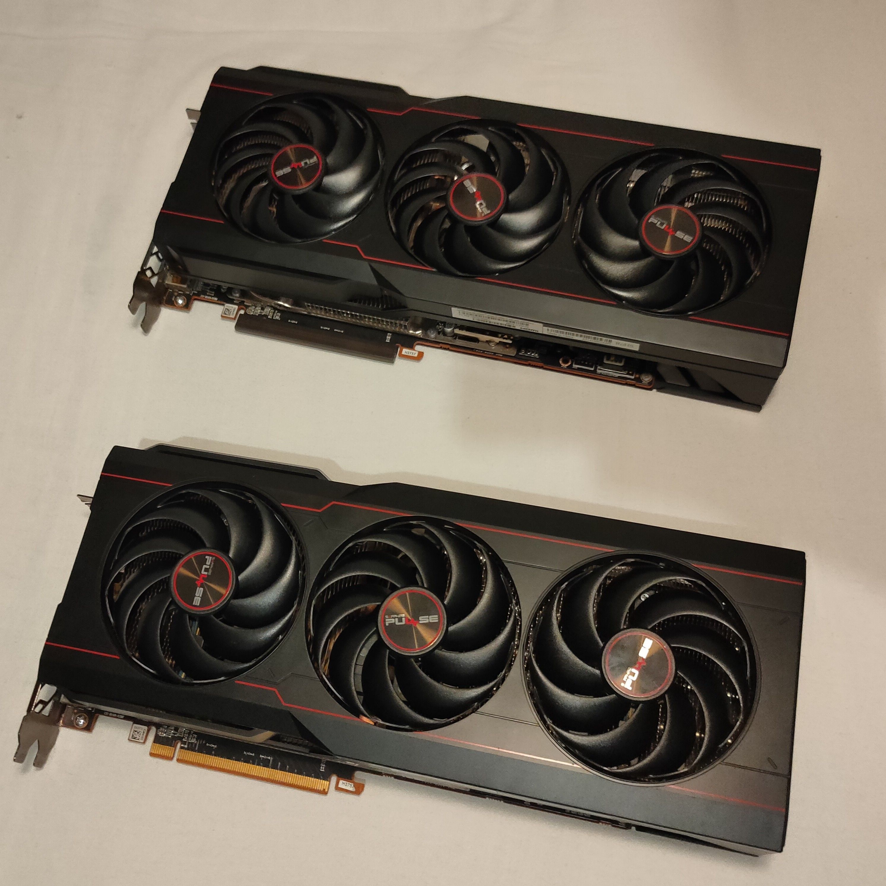 Two Sapphire Pulse RX 6800 XT graphics cards next to each other against a white background.