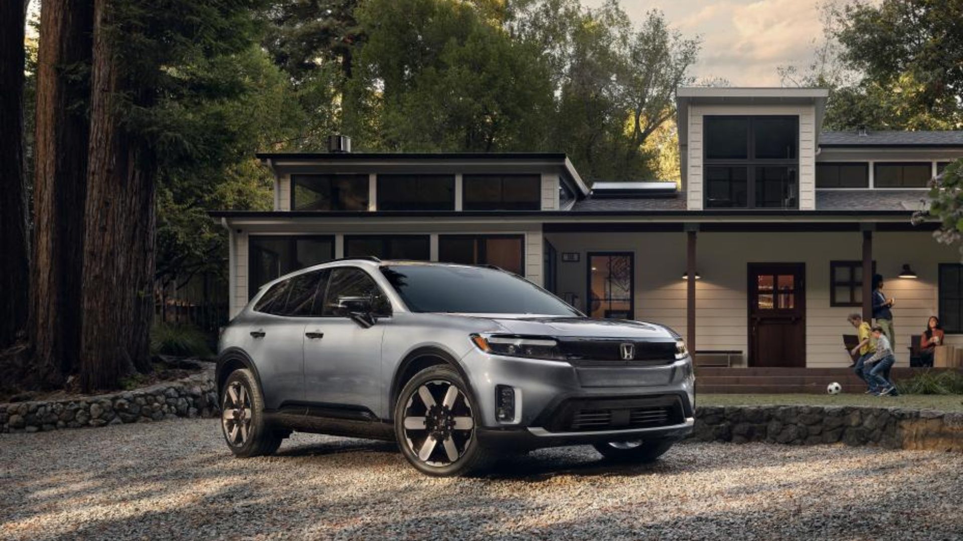 Silver Honda Prologue parked outside of a house with children playing alongside it.