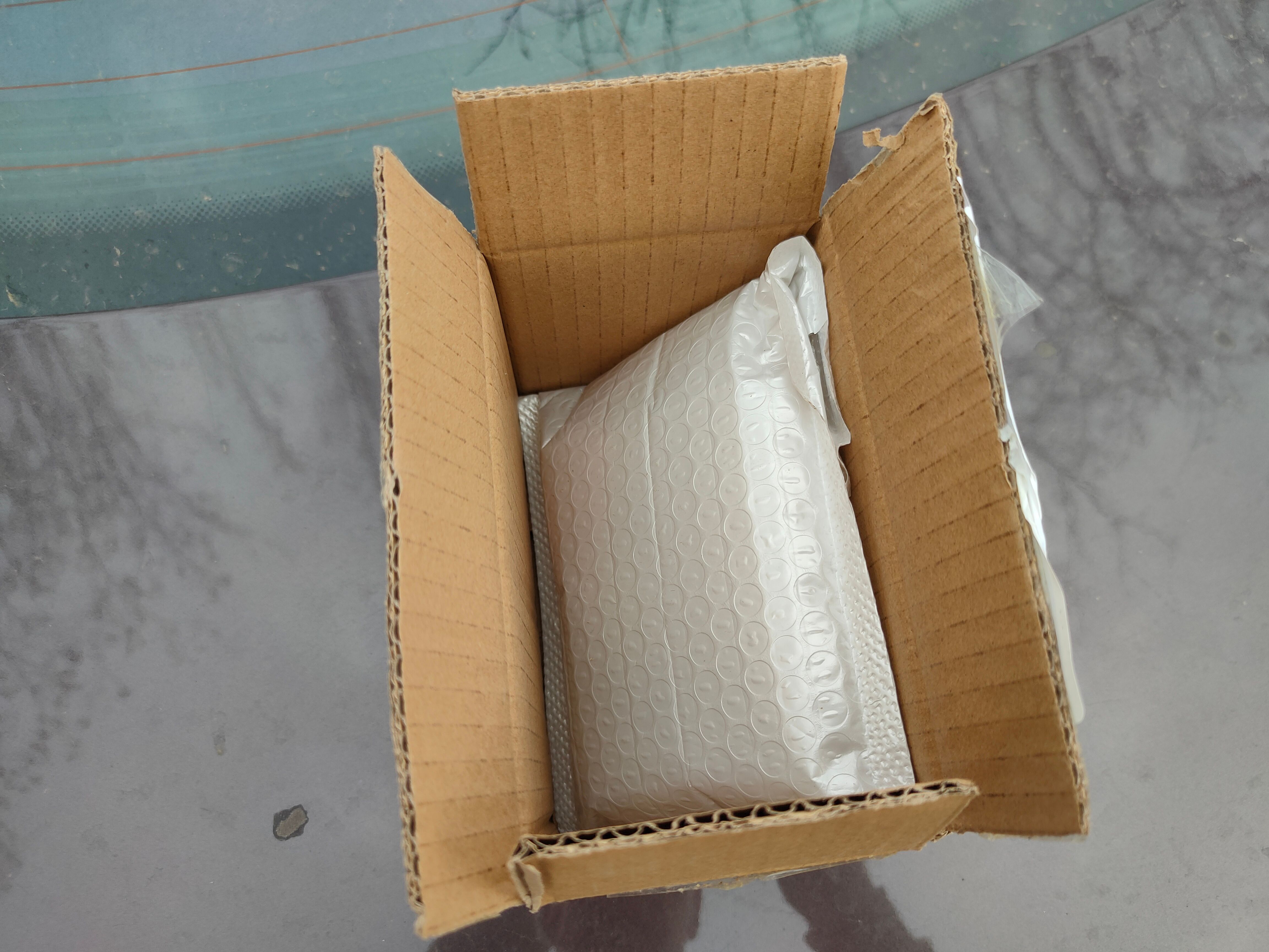 A white bubble wrap package containing a CPU inside of a brown cardboard box.