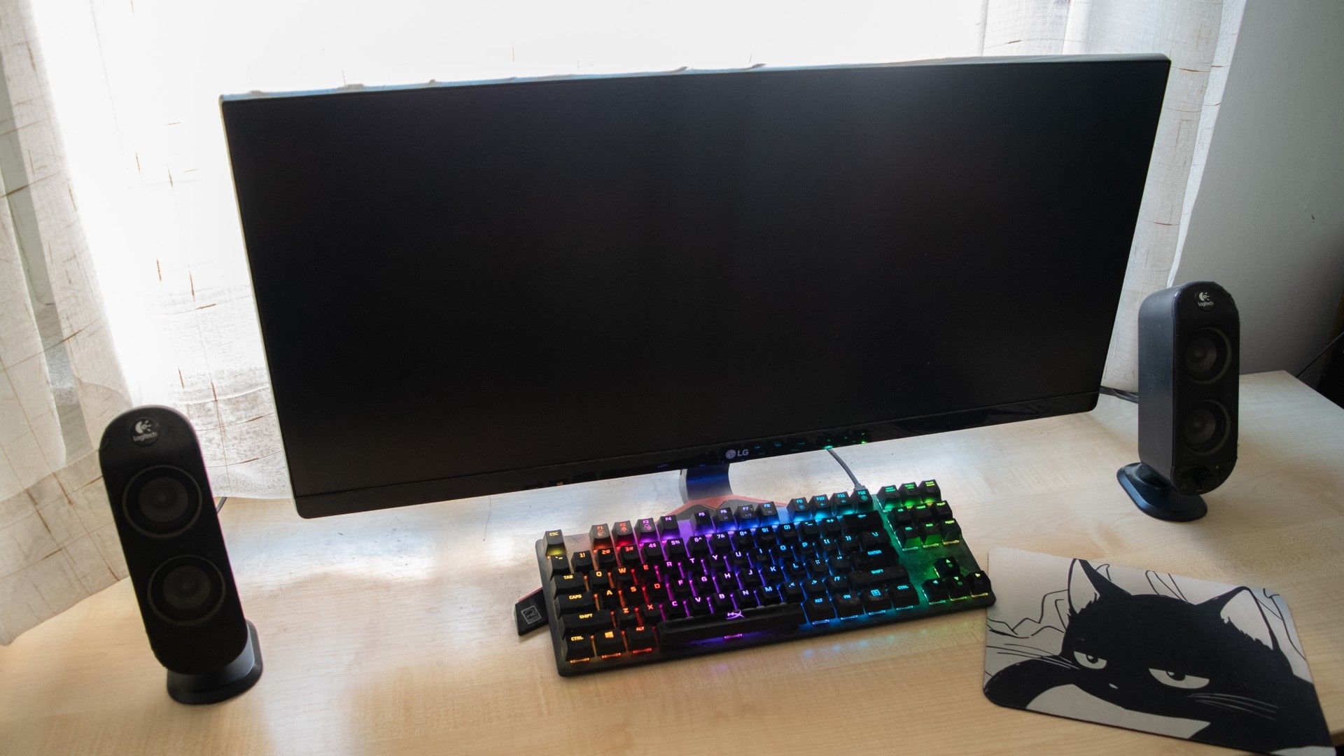 Logitech X230 Speakers sitting on a table with a monitor and a keyboard between them. 