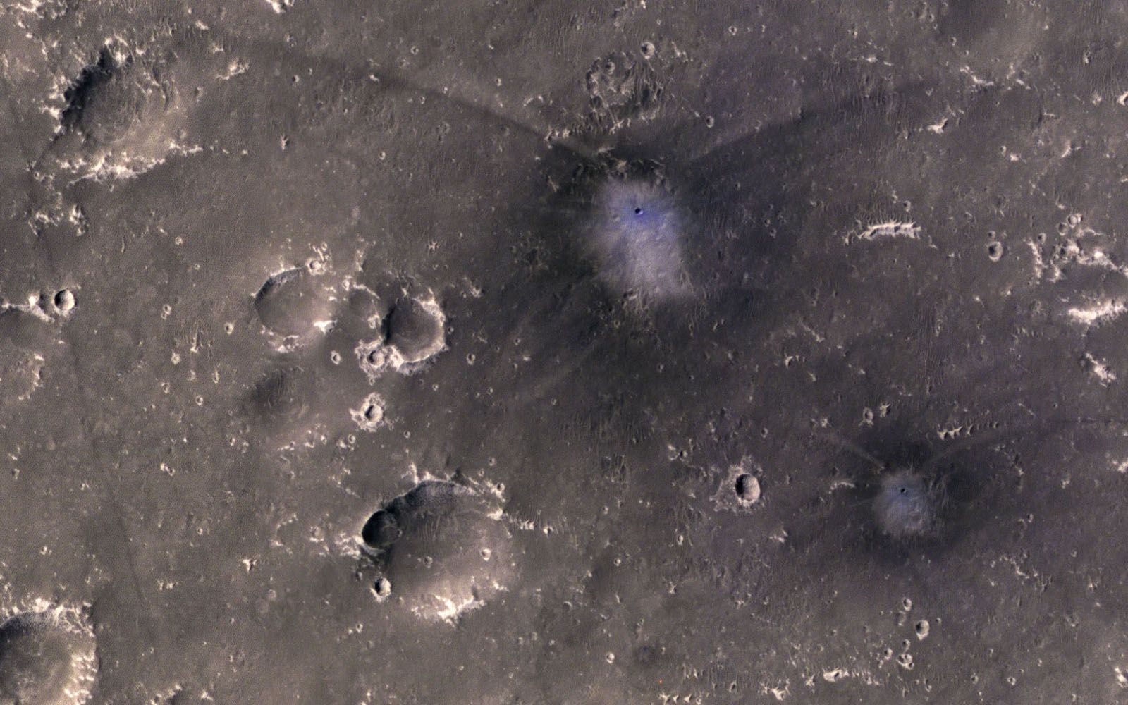 An image of several craters on the gray surface of Mars.