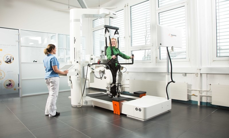 A robotic system attached to a patient's body, over a treadmill with support harness, used for gait rehabilitation training.