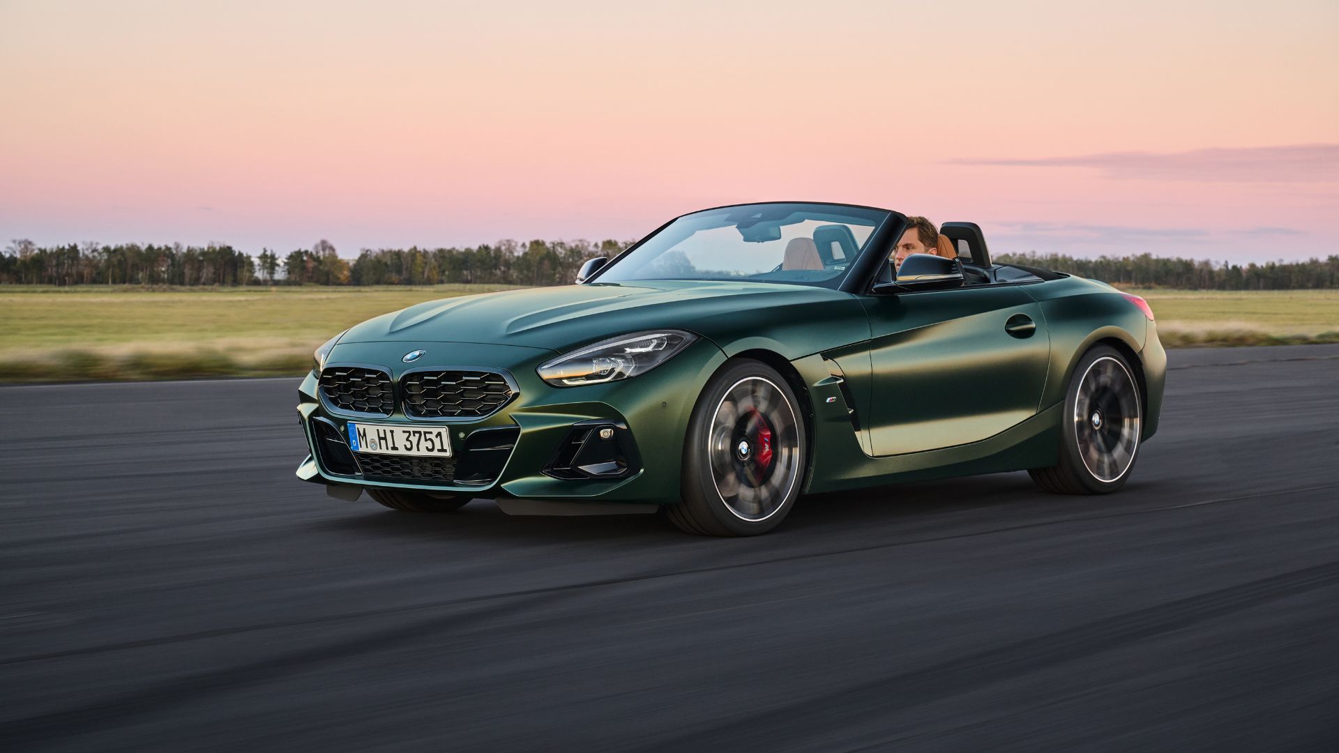 Full view of green BMW Z4 on an airfield.