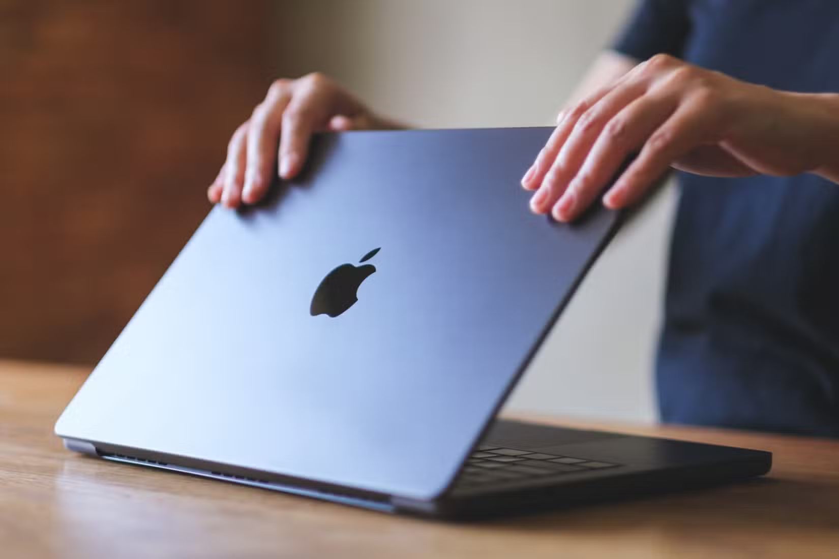 A person opening a MacBook's lid.