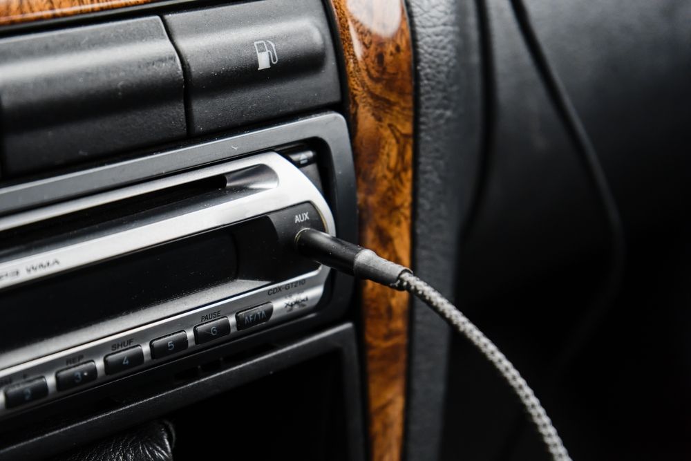 Car stereo system with aux input cable, media control buttons.