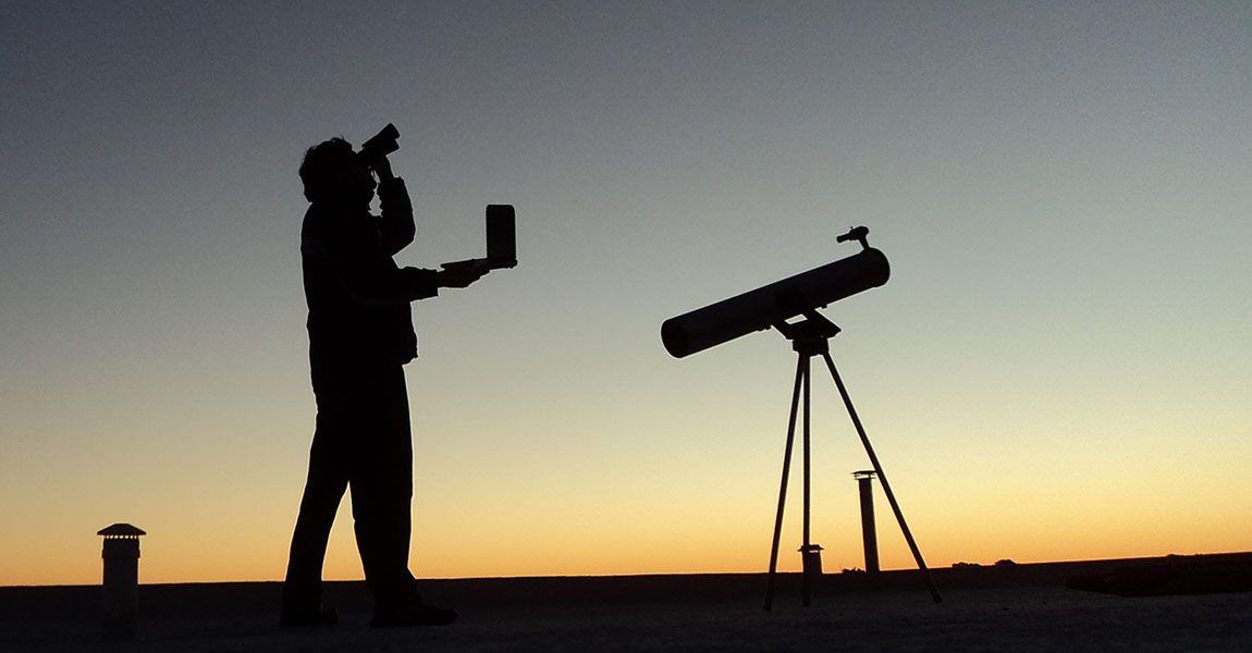 Someone using binoculars alongside a telescope.