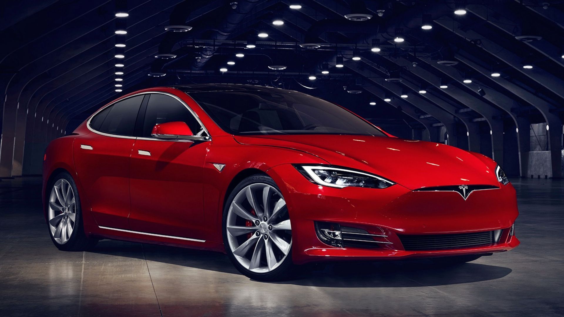 Full view of a red 2016 Tesla Model S P100D parked in a hangar.