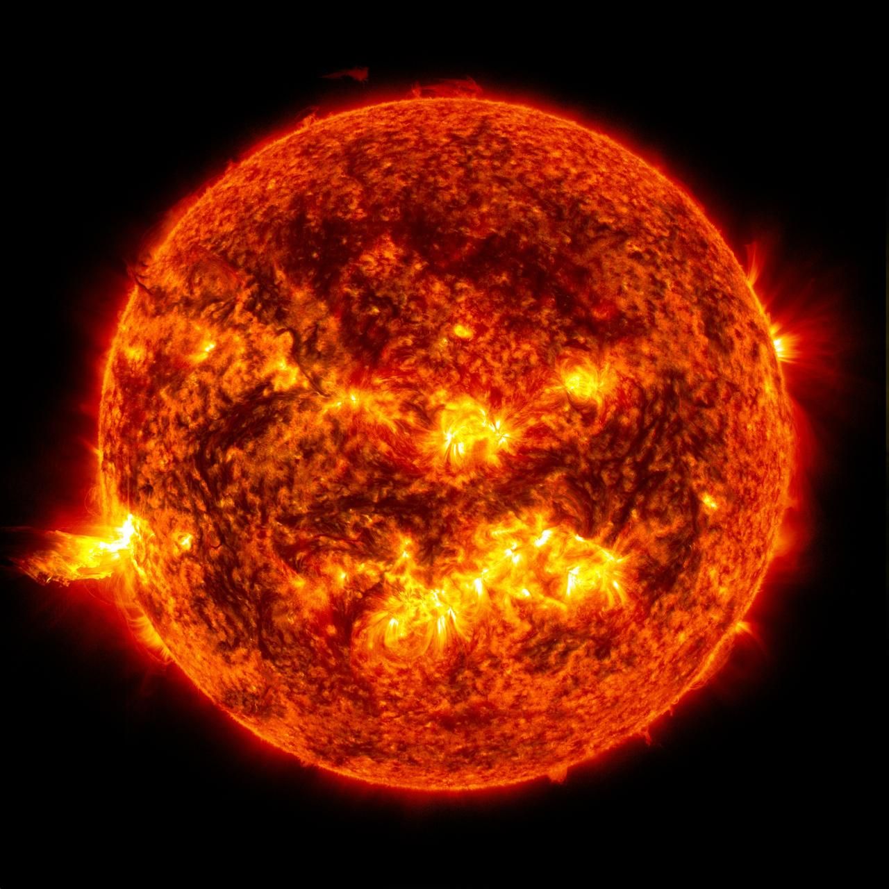 The Sun with a solar flare on the left-hand side and an eruption of solar material shooting through the star's atmosphere.