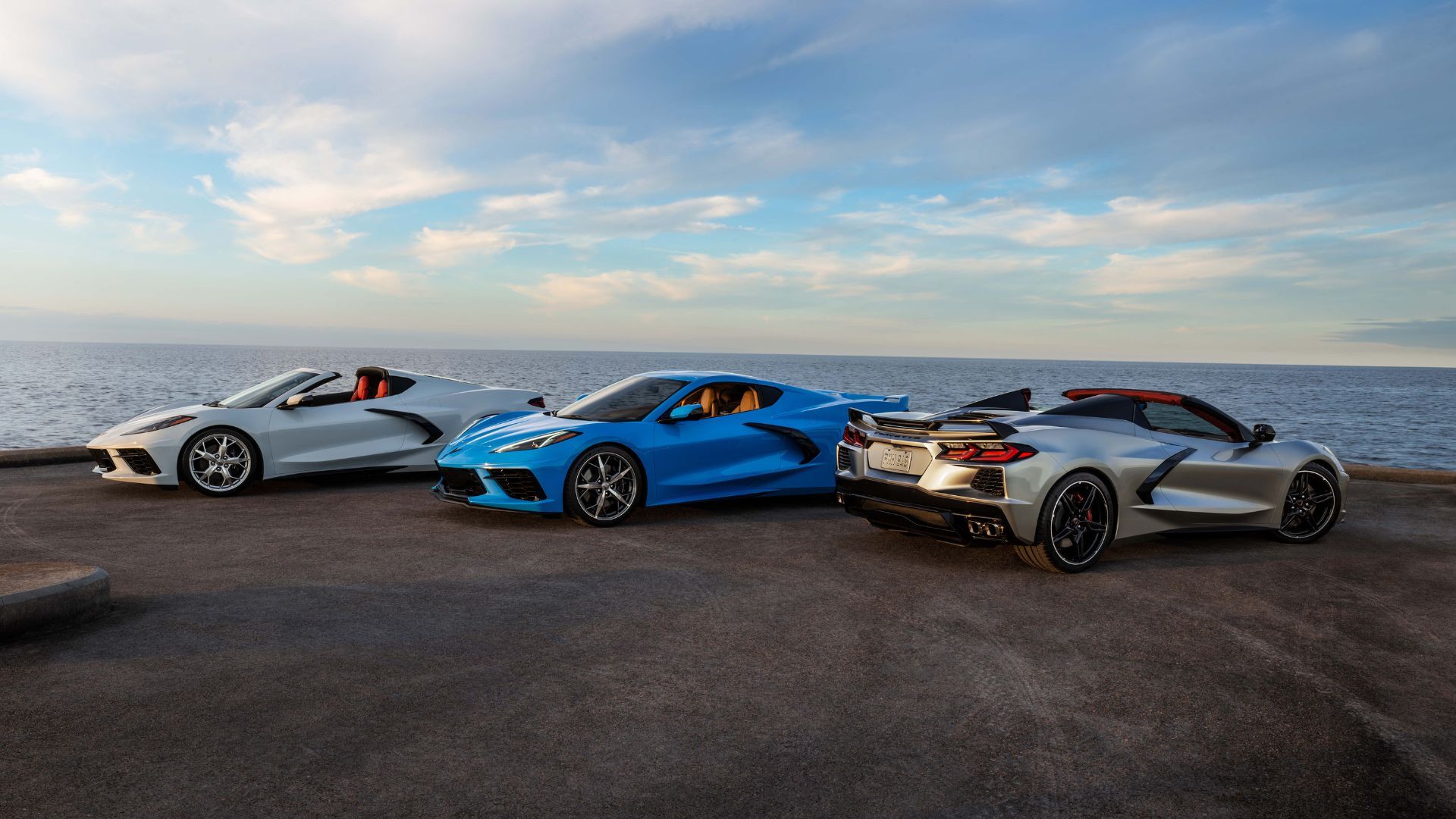 Coupe andf convertible variants of the 2021 Chevrolet Corvette Stingray parked together with the ocean in the background.