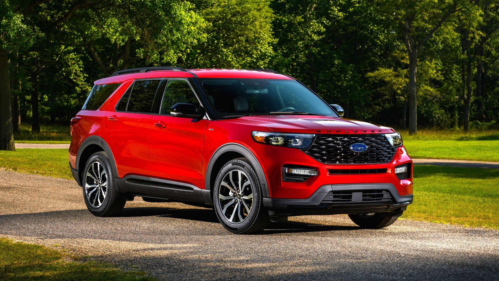 Front three-quarter view of a red 2022 Ford Explorer parked on gravel with trees in the background.