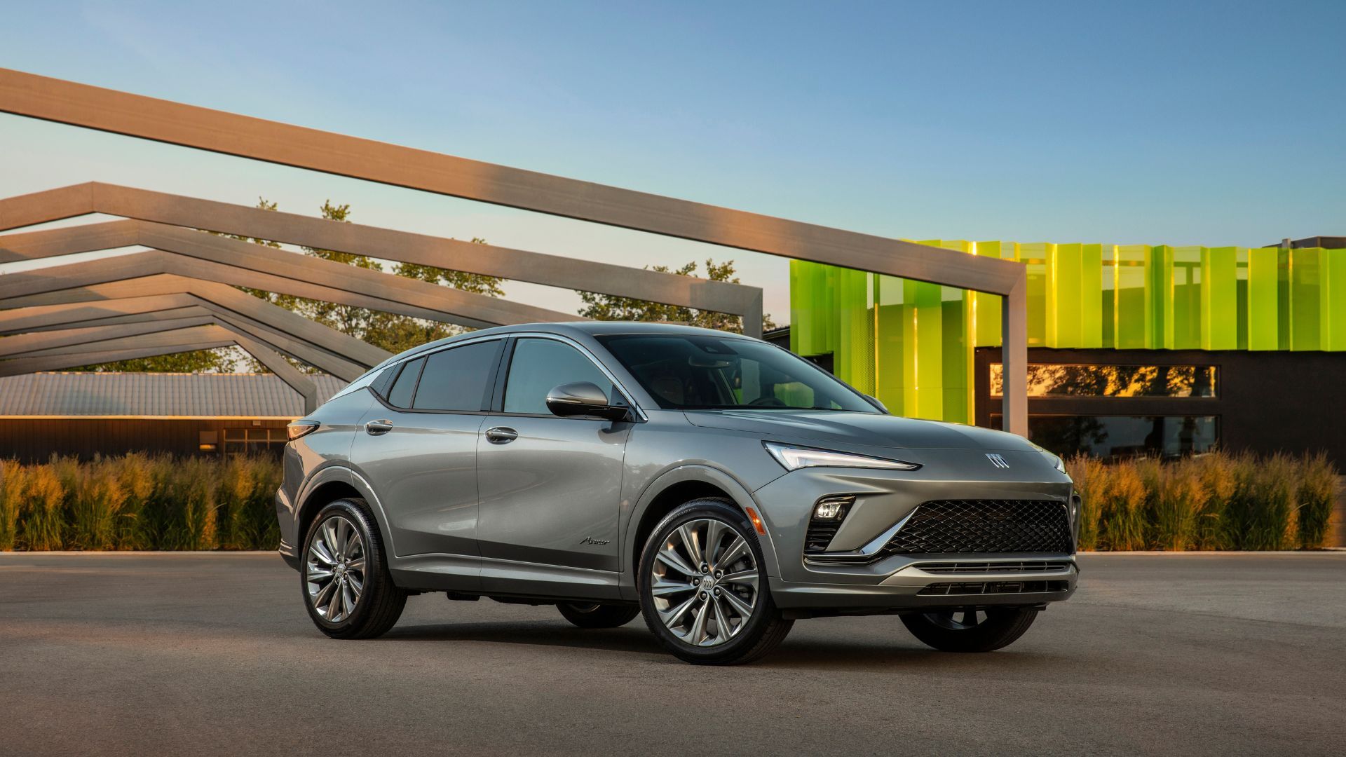 Front three-quarter view of a gray 2024 Buick Envista parked in betweeen modern architecture structures.