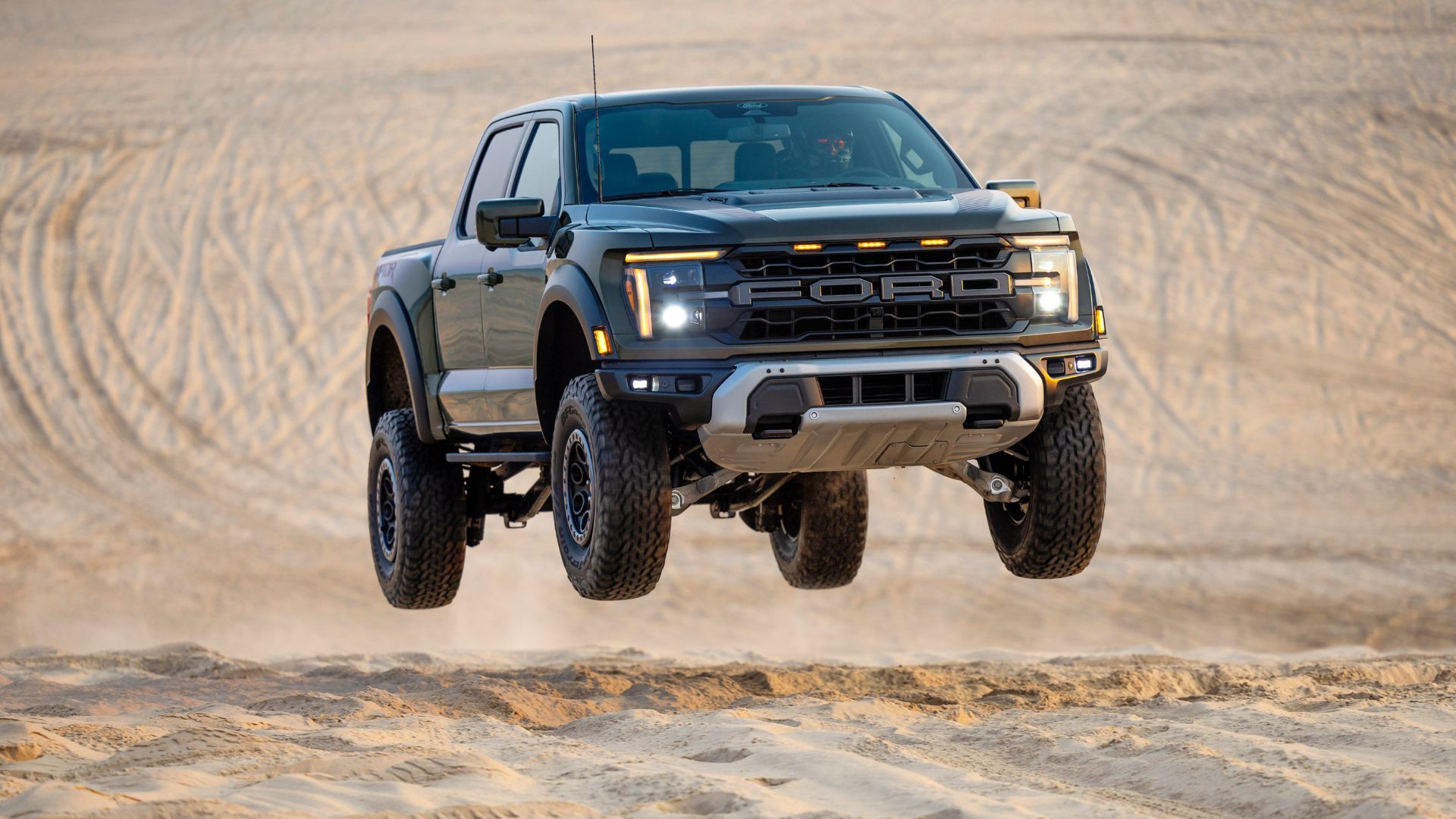 Full view of a 2024 Ford F-150 Raptor lifting off in sand dunes.