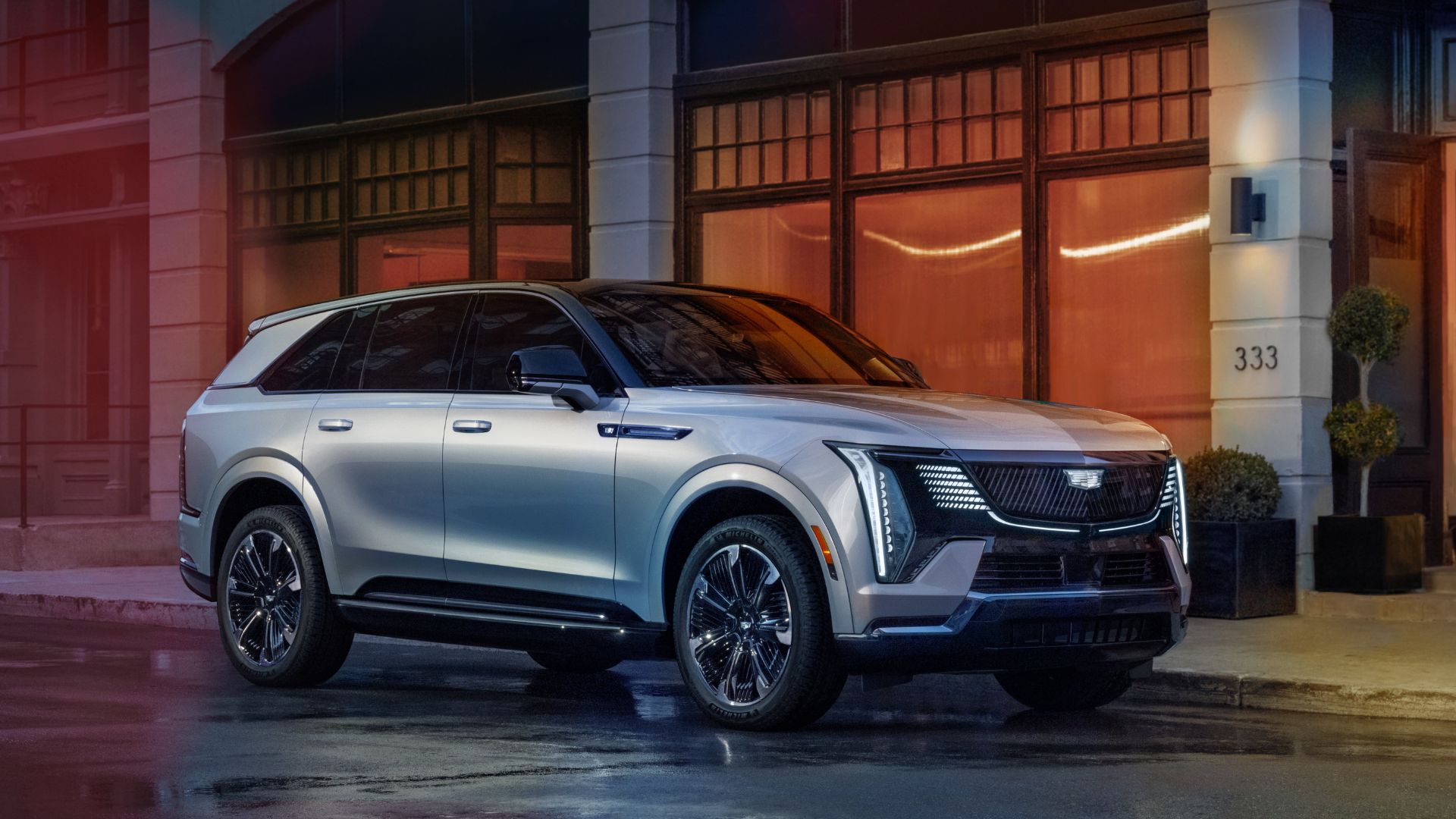 Full view of a 2025 Cadillac Escalade IQ parked alongside a sidewalk in a city.