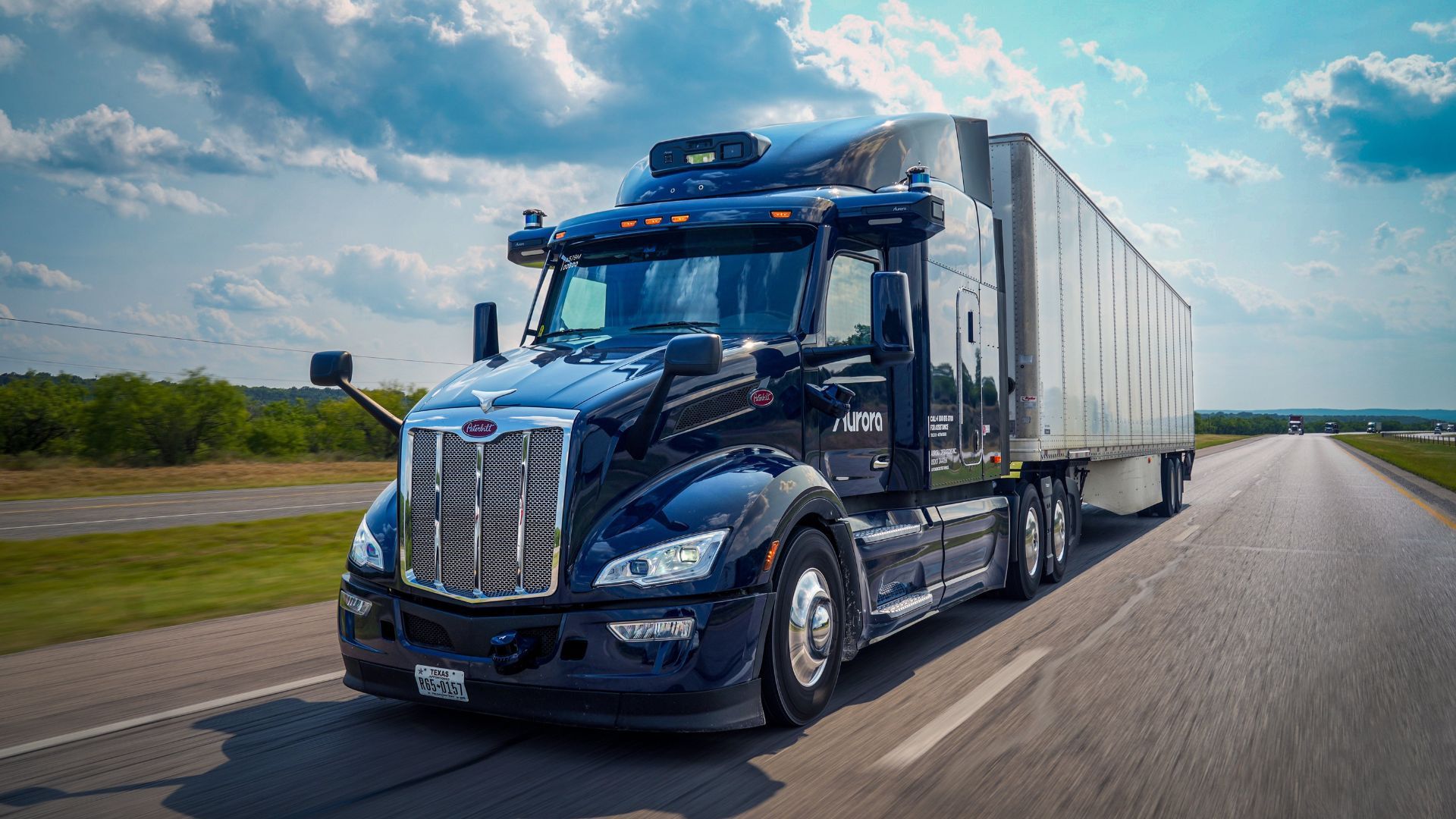 Full view of an Aurora driverless truck driving on a highway.