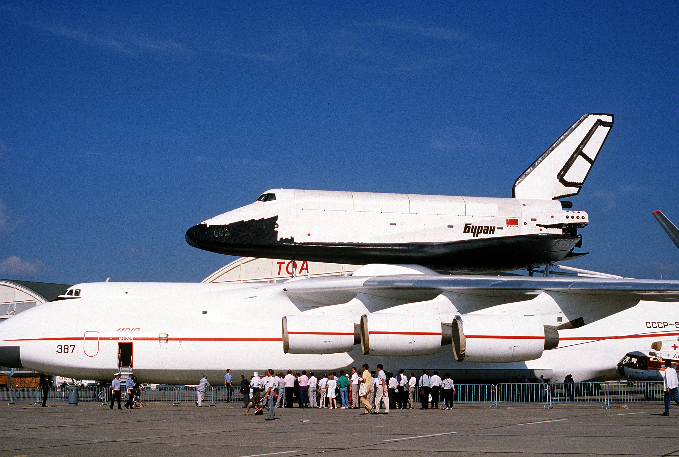 Visitors at the 38th Paris International Air and Space Shown at Le Bourget Airfield line up to tour a Soviet An-225 Mriya aircraft with the Space Shuttle Buran on its back.