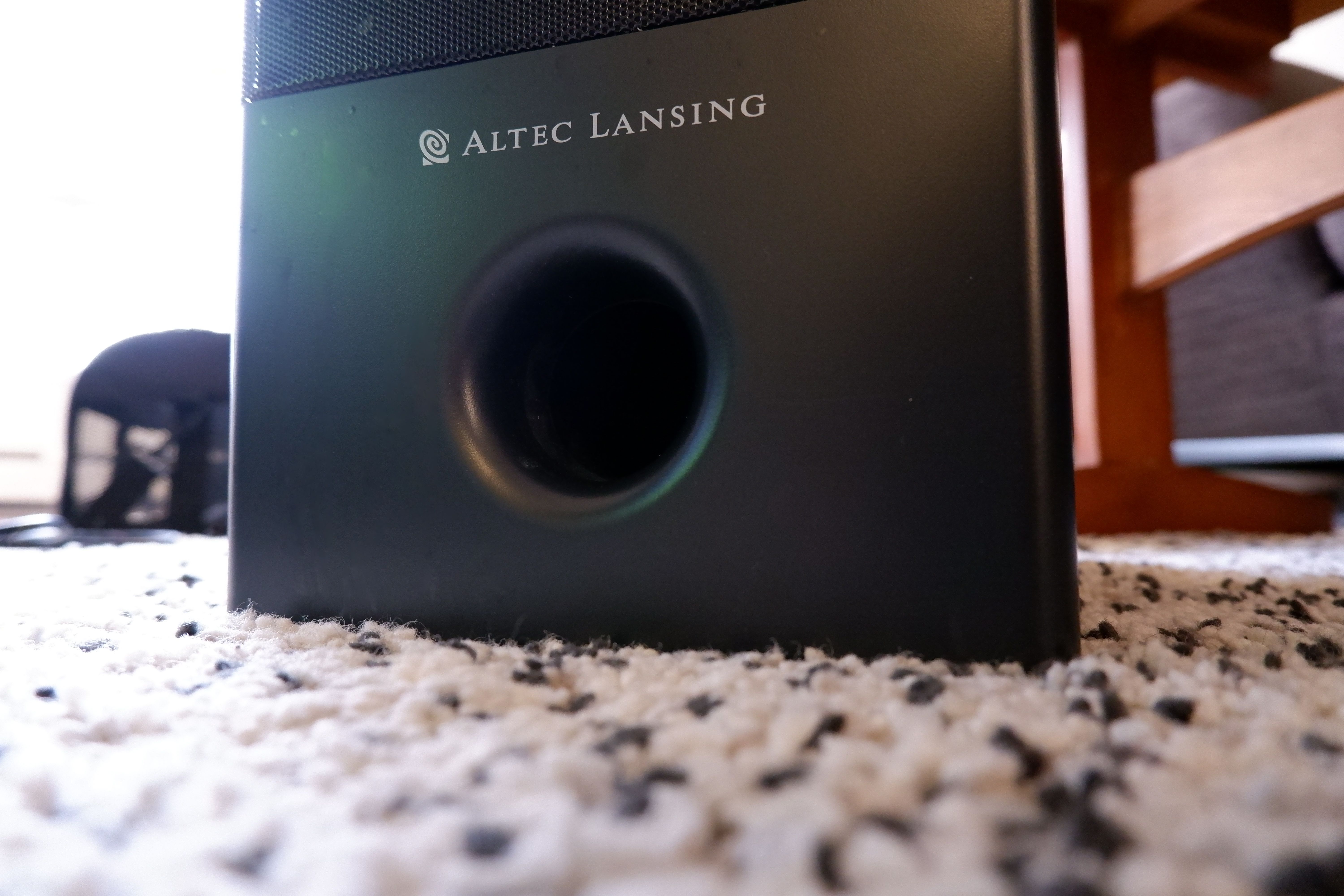 A subwoofer on a white speckled carpet