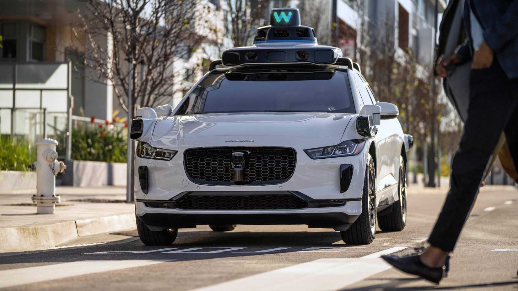 Before a Waymo Jaguar I-Pace stopping for a pedestrian crossing the road.