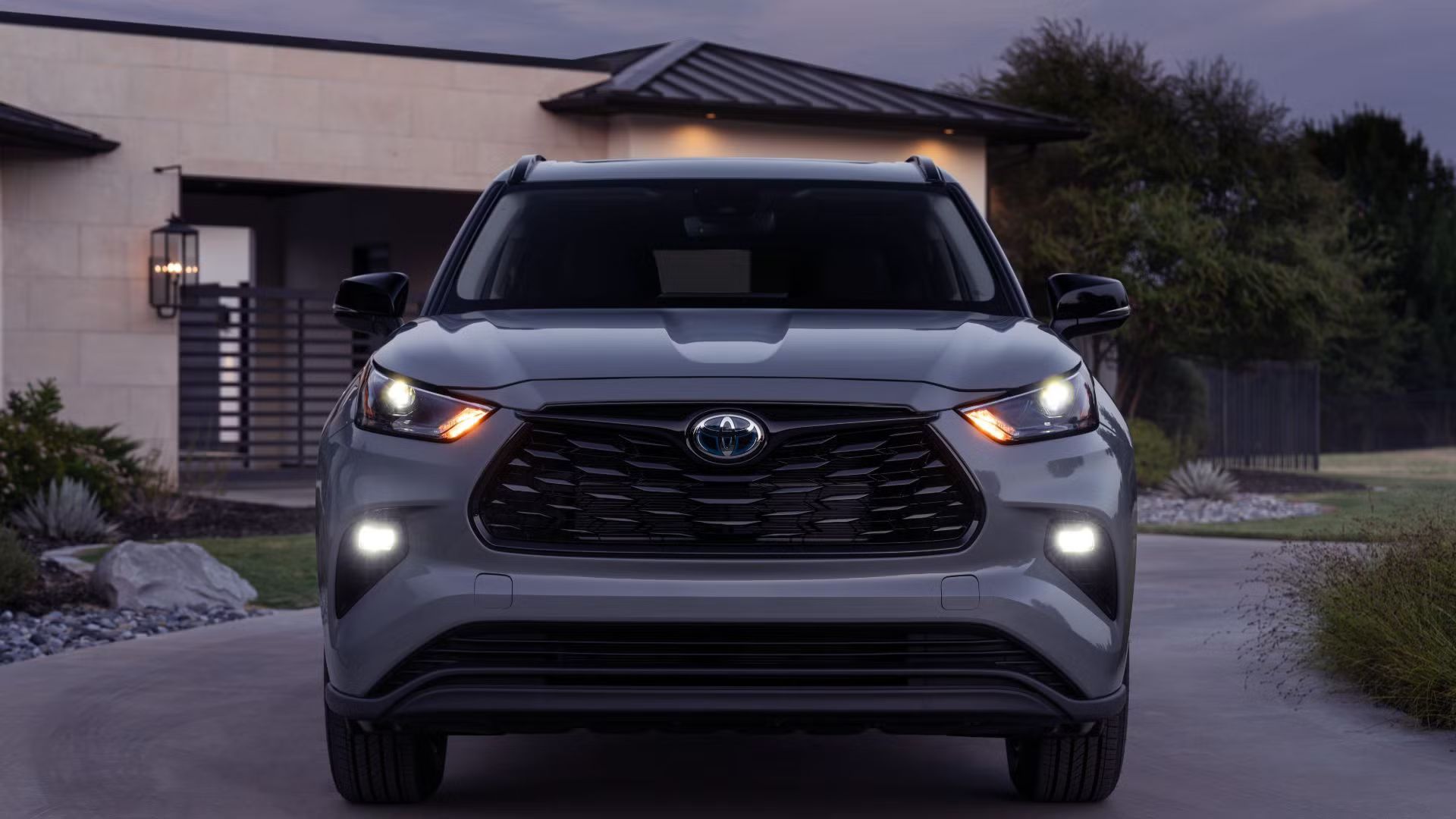 Вид спереди серого Toyota Highlander 2024 года, припаркованного у дома
