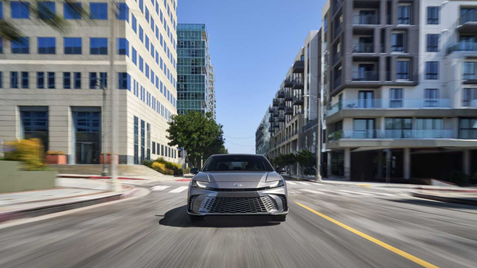 Front-end shot of a gray 2025 Toyota Camry XSE driving through a city.