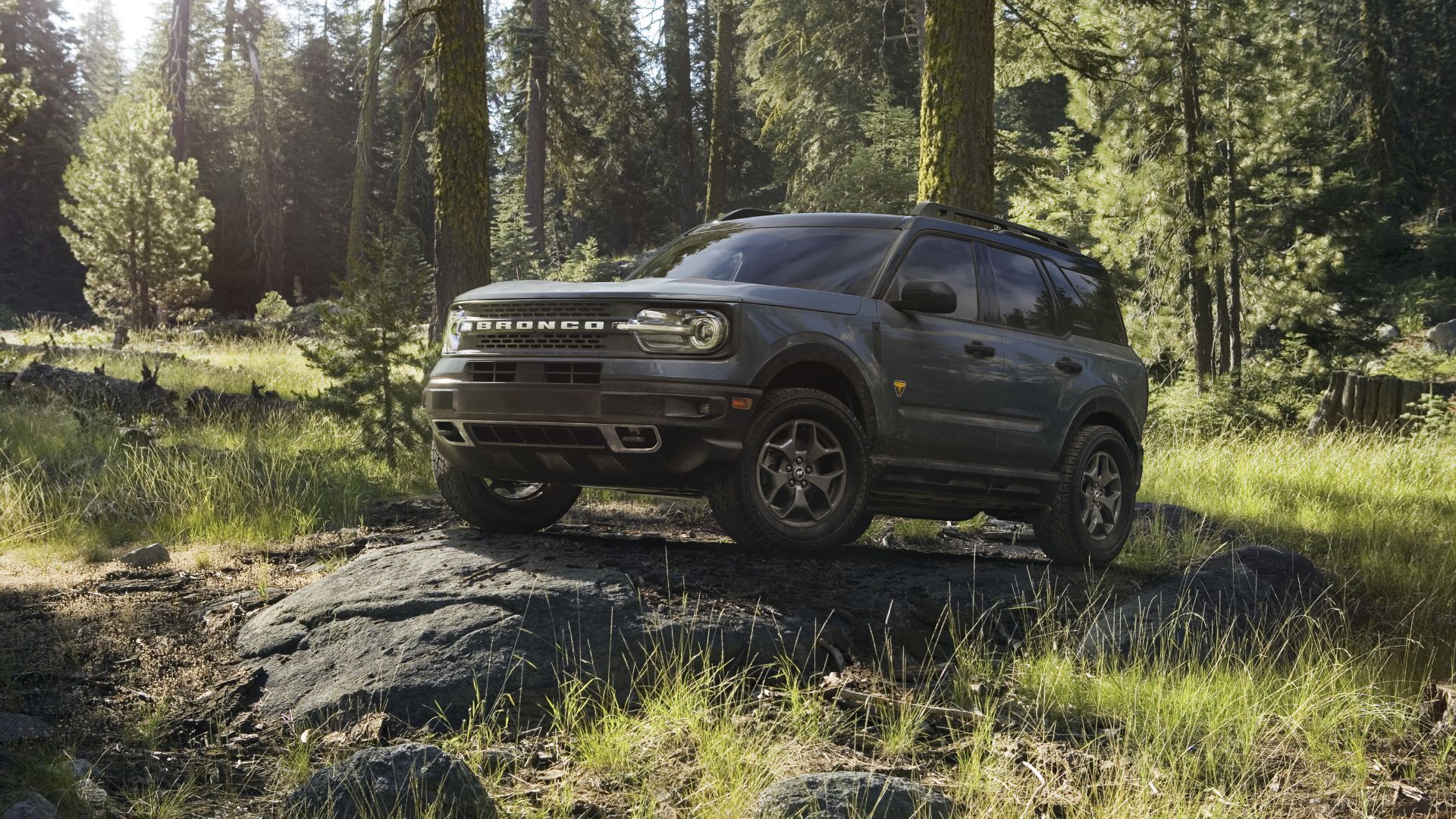 Front 3/4 view of a gray 2022 Ford Bronco Sport parked on a rock in a forest.