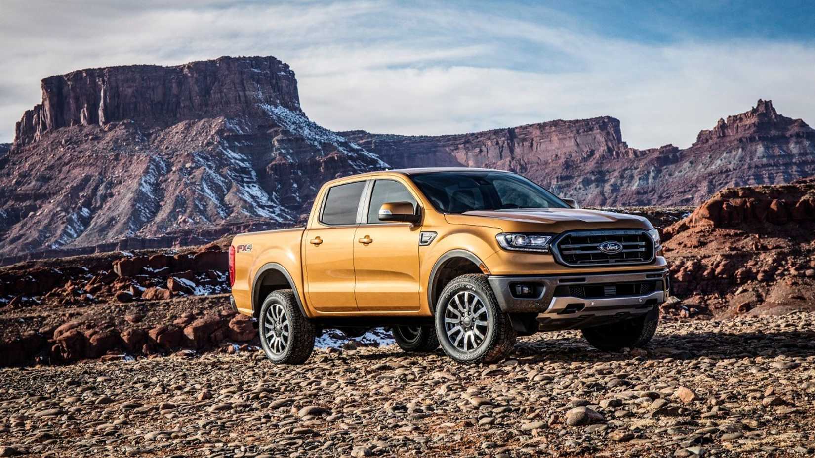 Front 3/4 view of an orange 2018 Ford Ranger parked on gravel with mountains in the background.