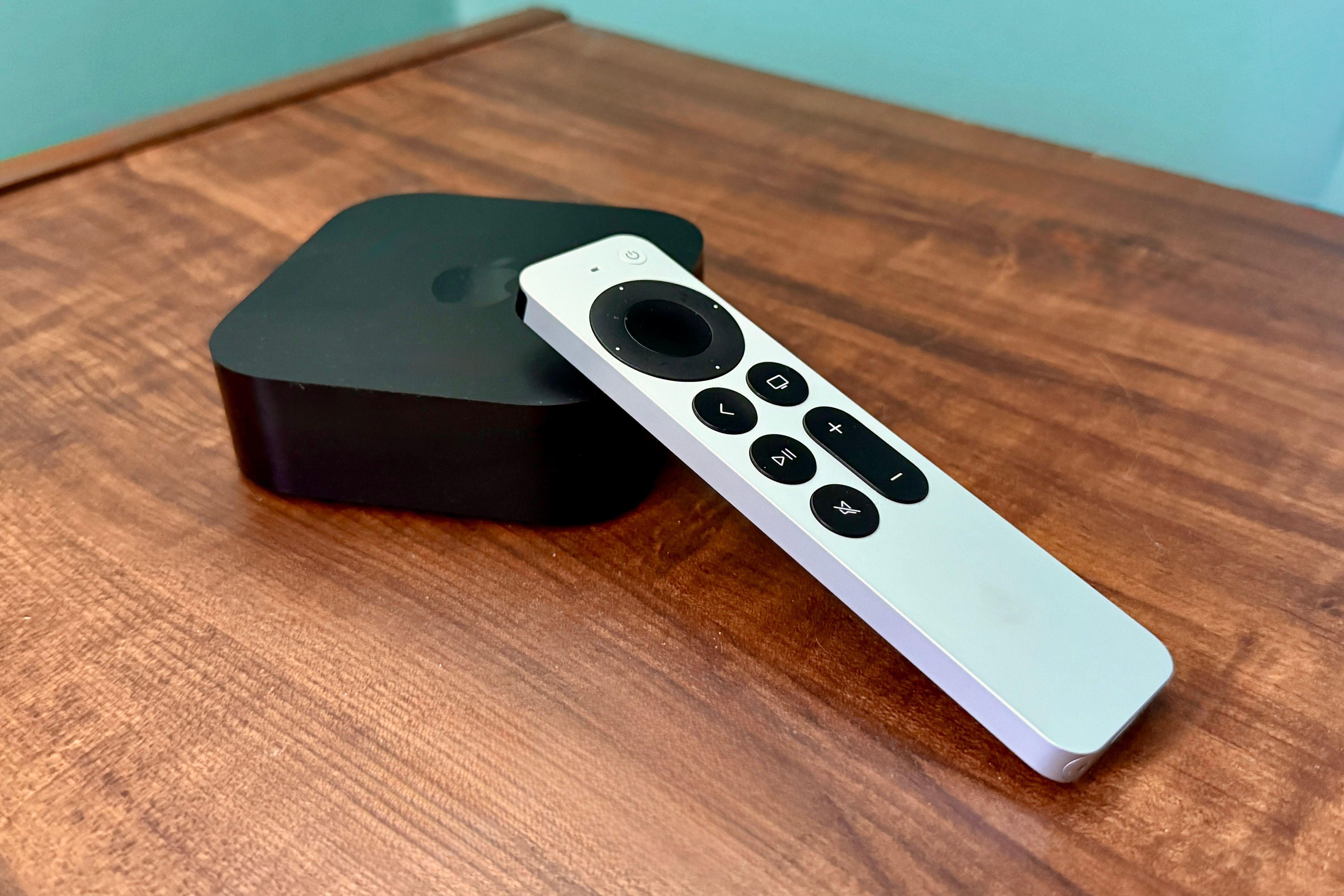 Apple TV 4K and remote control on a wooden table.