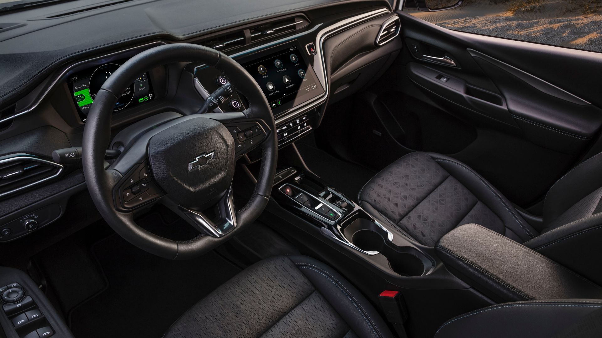 Close-up shot of inside the cabin of a 2022 Chevrolet Bolt EV, showing the front seats, steering wheel, and infotainment screen.