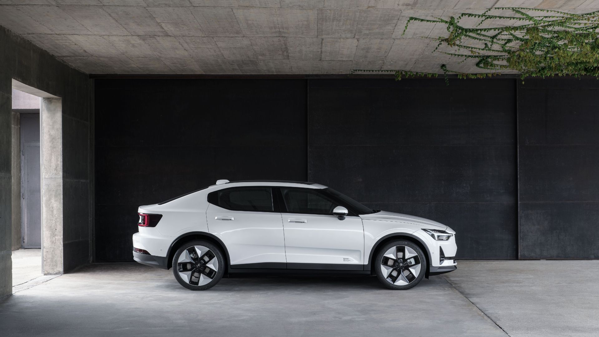 Static side profile shot of a white 2023 Polestar 2 parked partially indoors.