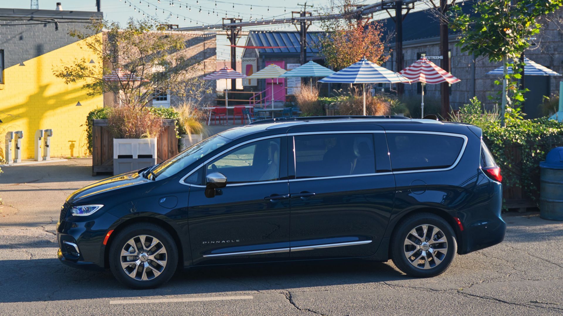 Static side profile shot of a dark blue 2025 Chrysler Pacifica Plug-In Hybrid Pinnacle parked in a city.