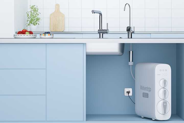 A water water filter below a sink in a blue kitchen