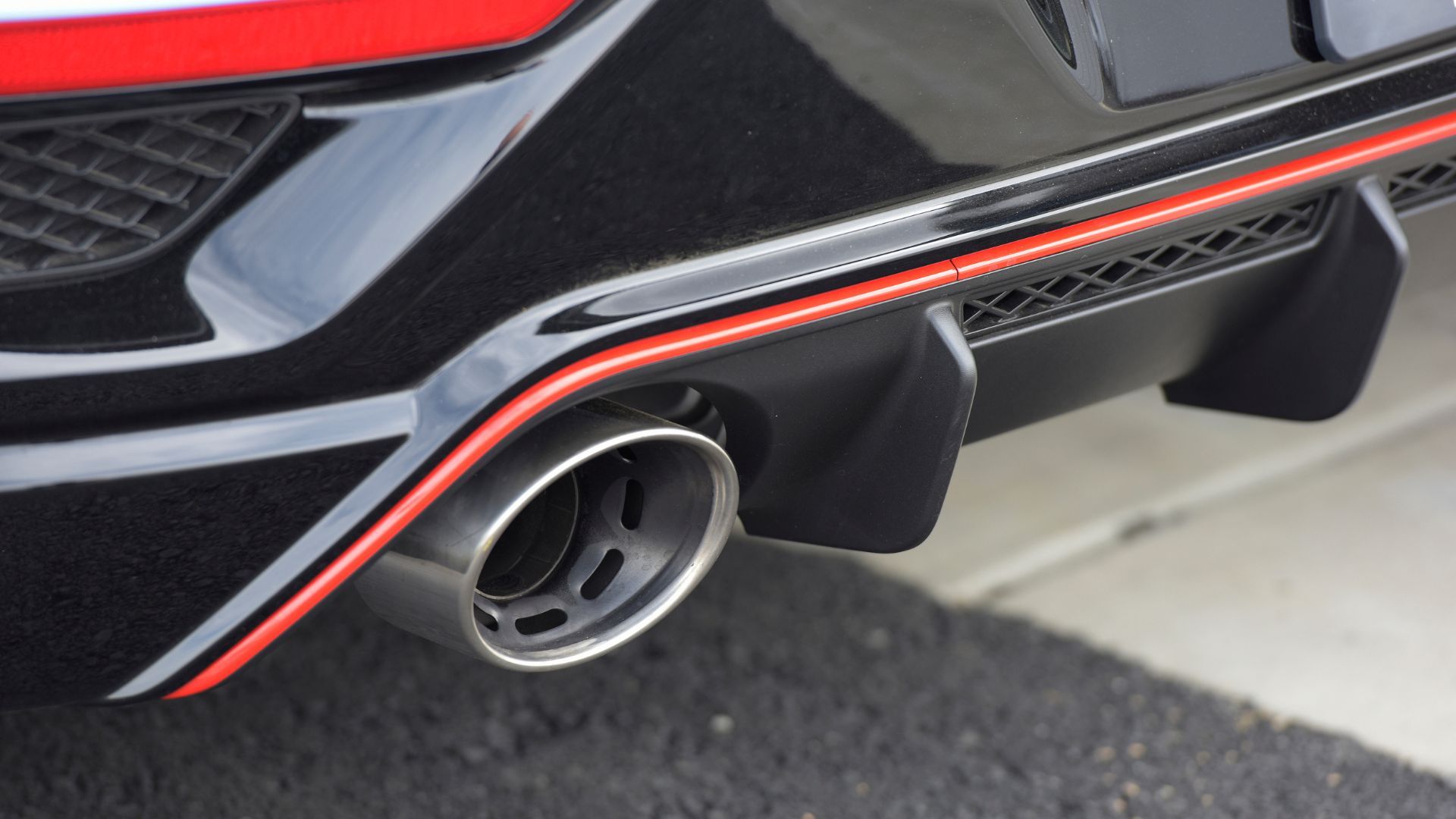 Close-up shot of one of the exhaust tips and rear diffuser on a blue 2022 Hyundai Veloster N.