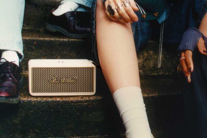 People sitting on stairs listening to a The marshall middleton Il with a close up on the speaker