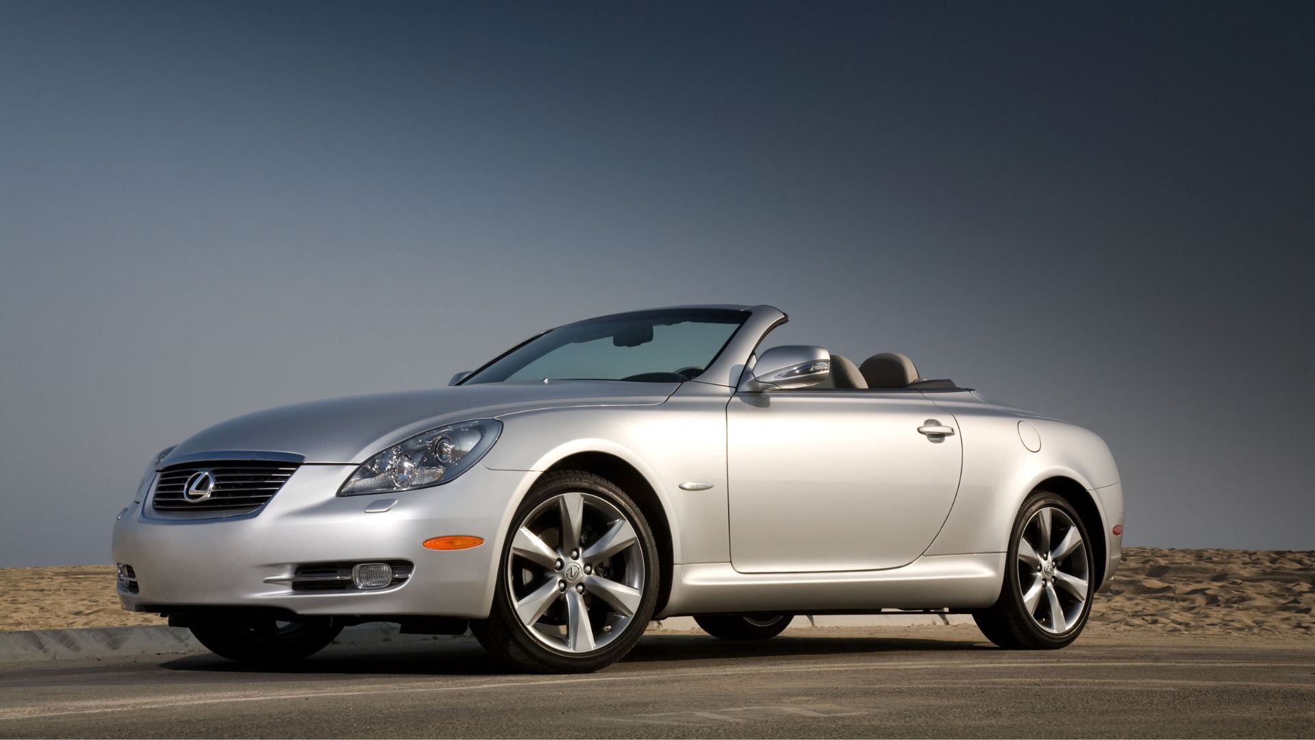 Static front 3/4 shot of a silver 2010 Lexus SC 430 parked on tarmac in the desert.