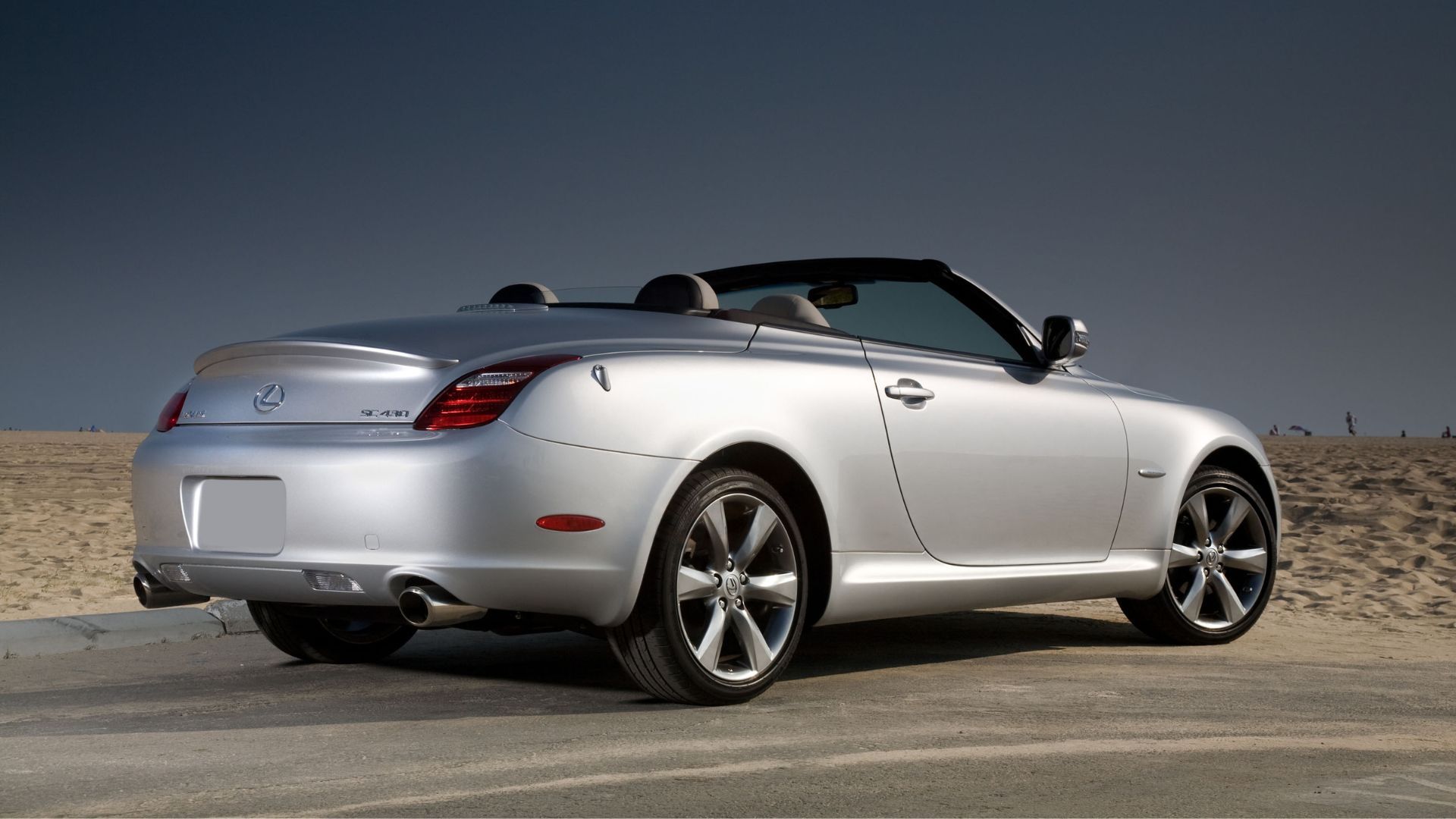 Static rear 3/4 shot of a silver 2010 Lexus SC 430 parked on tarmac in the desert.