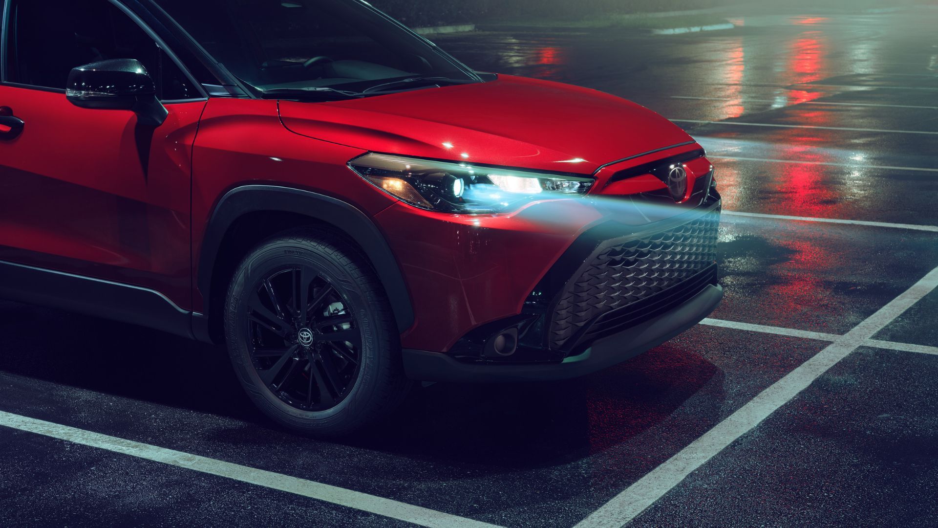 A red 2024 Toyota Corolla cross nightshed's close-up shot with its headlights shining at night.