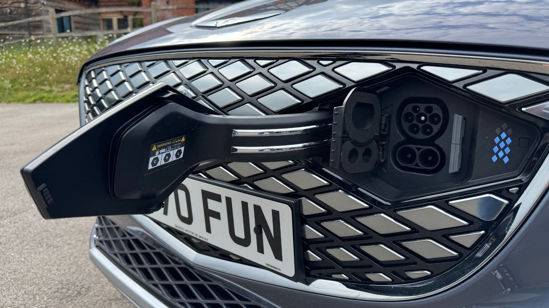 Close-up shot of the charging port on the front of a gray 2026 Genesis Electrified GV70.