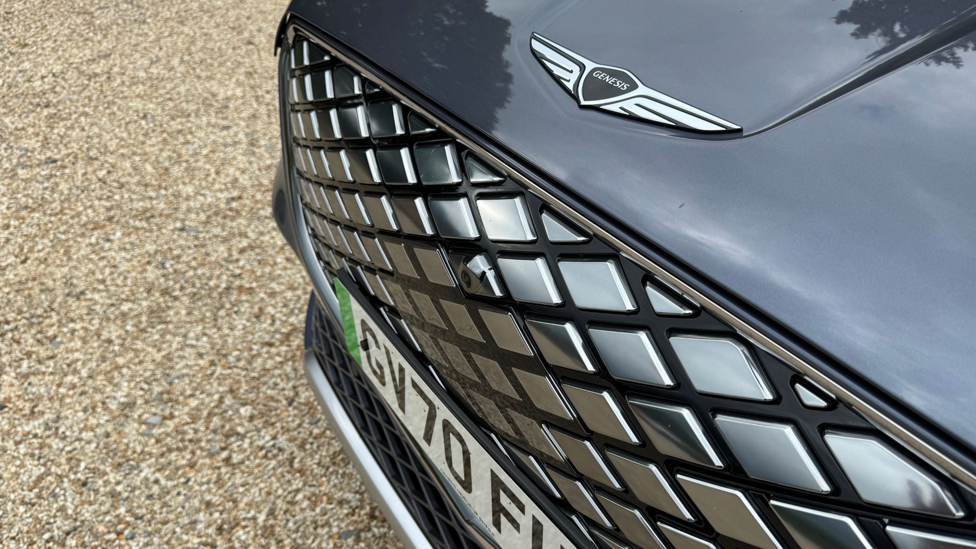 Close-up shot of the front grille on a gray 2026 Genesis Electrified GV70.