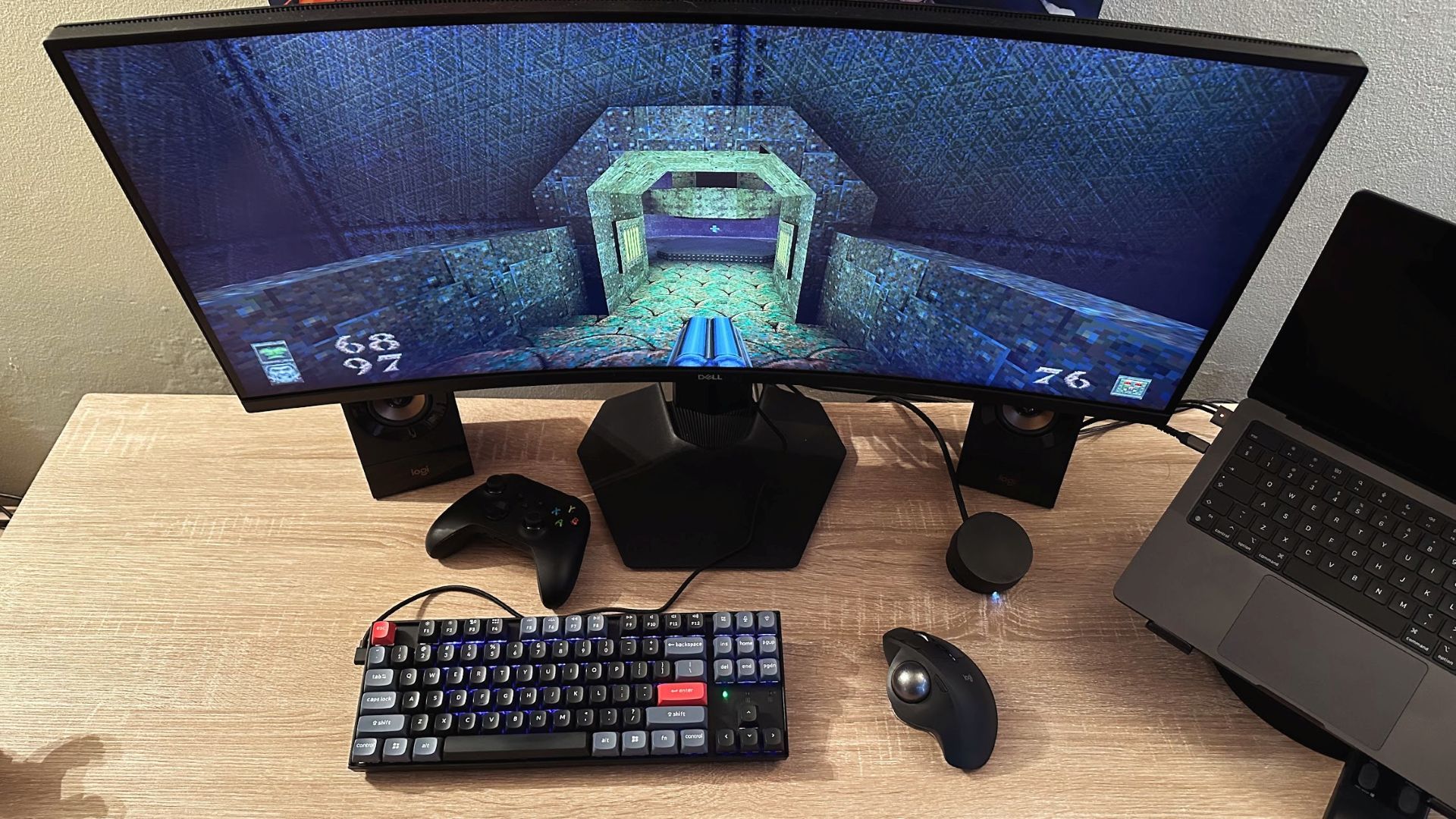 A desk with a gaming setup showing Quake on screen and a trackball mouse.