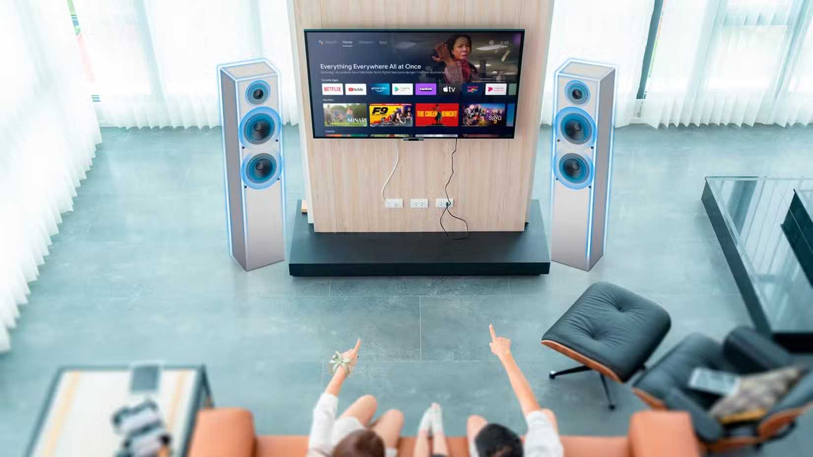 Una familia sentada en el sofá viendo televisión con los altavoces destacados.