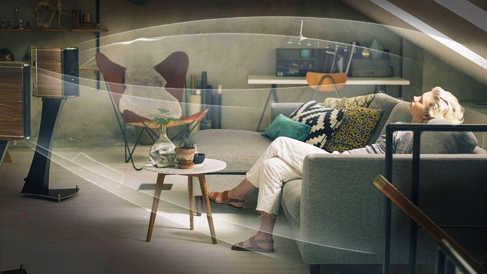 Una mujer sentada en su sofá después de que Dirac Live ajustó la configuración de su altavoz.