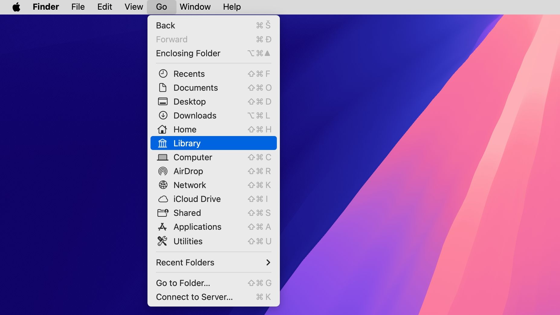 The desktop on macOS with the Finder's Go menu displaying various options, with the Library option selected.