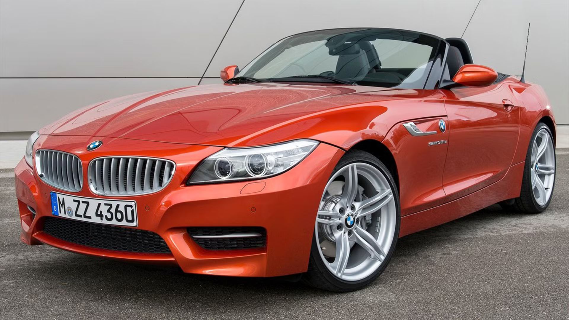 Stayic front 3/4 shot of an orange BMW Z4 with its roof folded down.