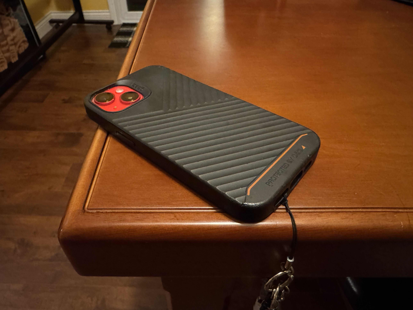 An iphone with a black case laying face down on a counter.