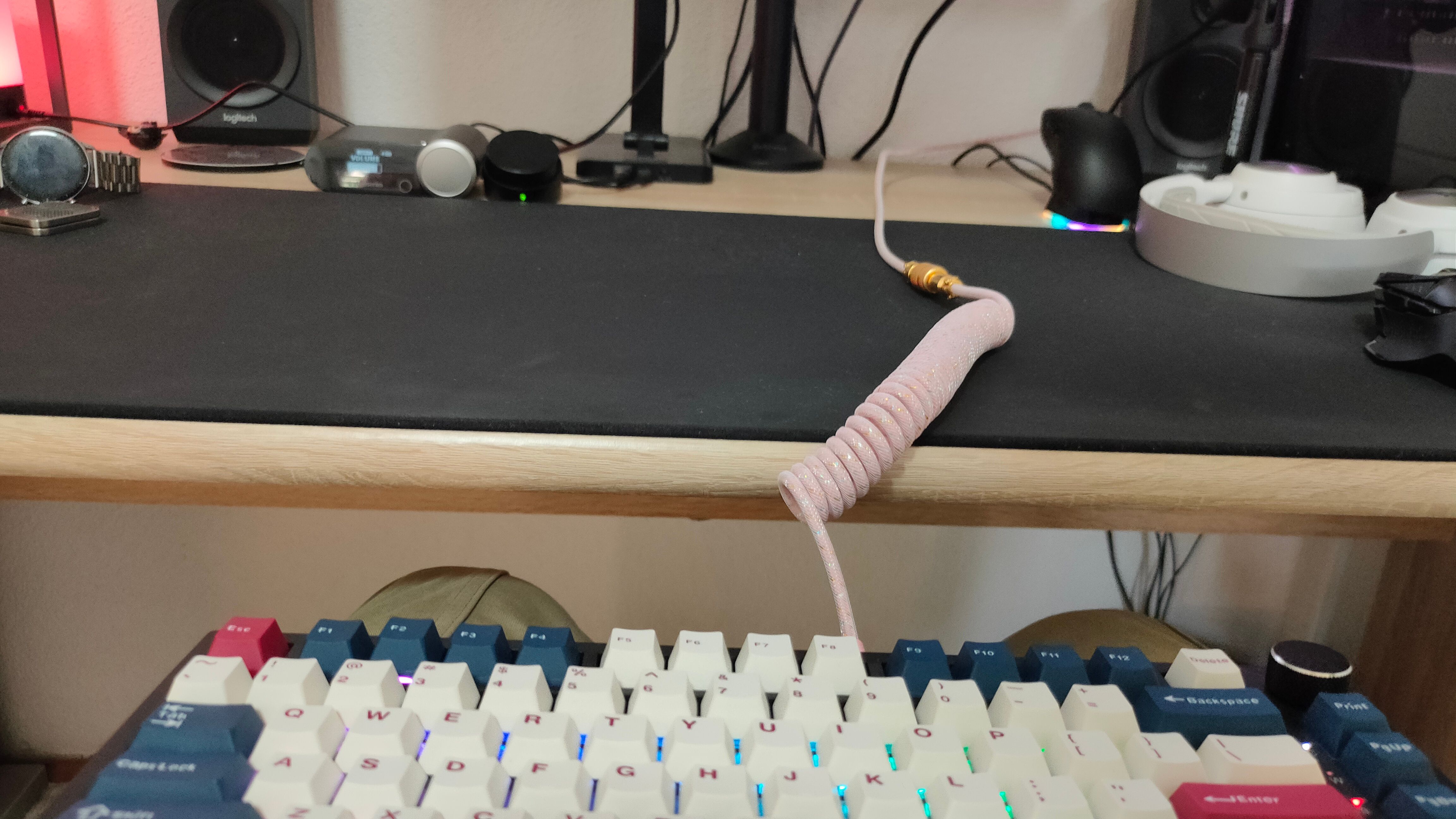 A keyboard in a lap with a coiled cable going over a black mousepad.