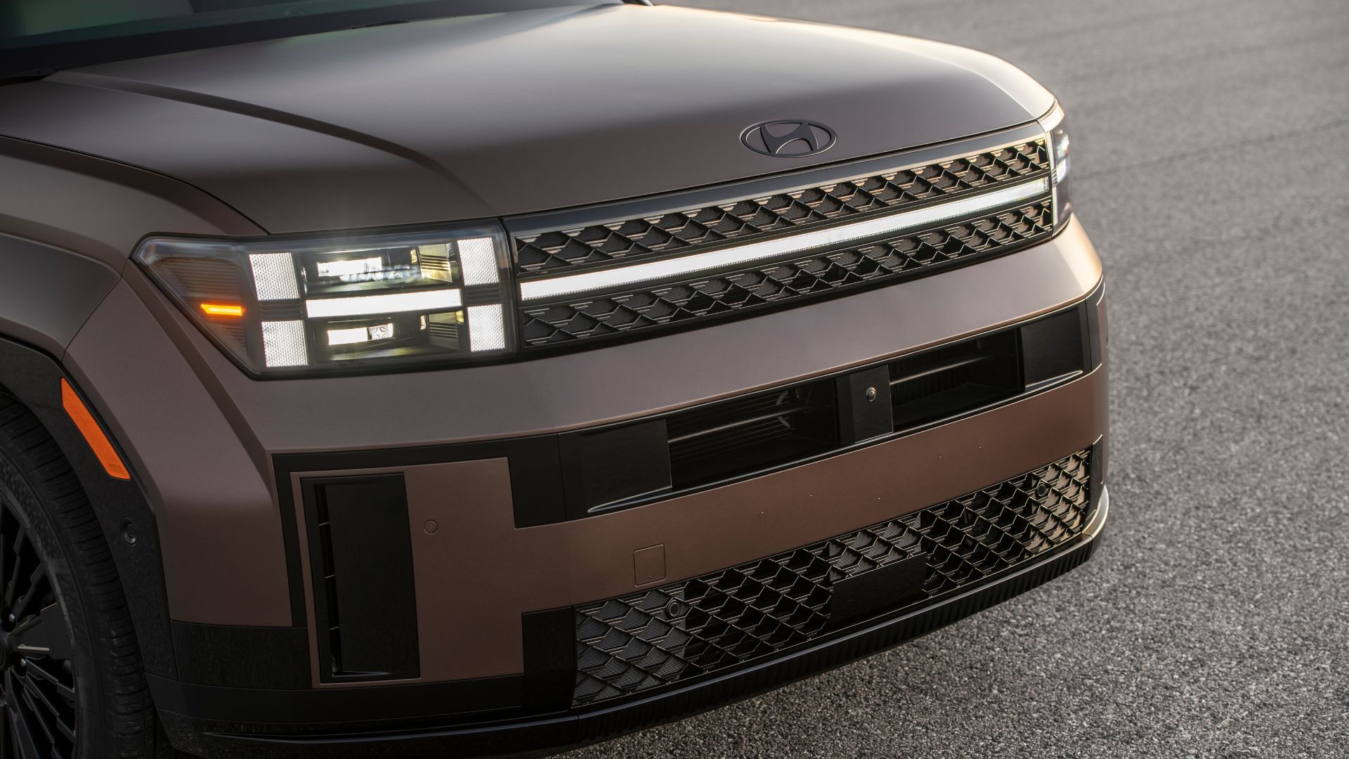 Close-up shot of the frotn end of a bronze 2025 Hyundai Santa Fe Hybrid.
