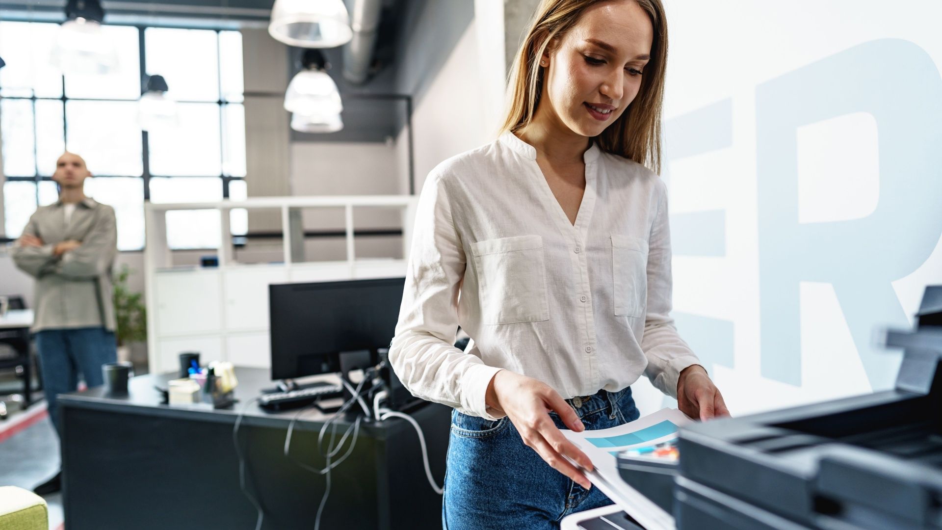 Young employee using modern printer in office.