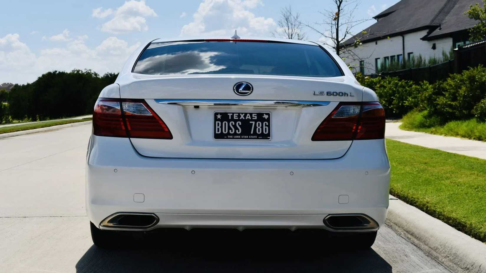 Static rear-end shot of a white 2011 Lexus LS 600h L parked next to a sidewalk.