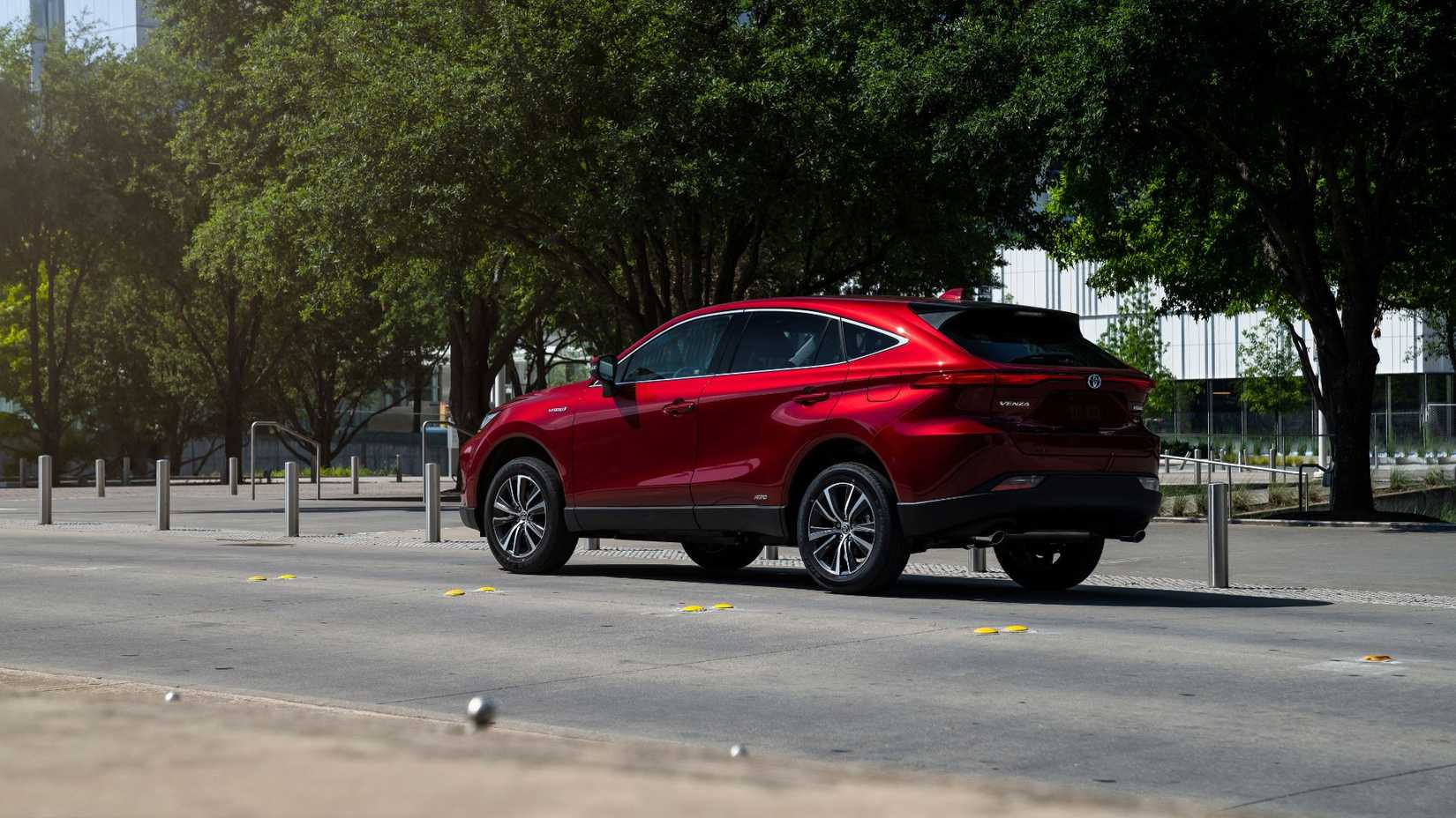 Static rear 3/4 shot of a red 2021 Toyota Venza parked on a street in a city.