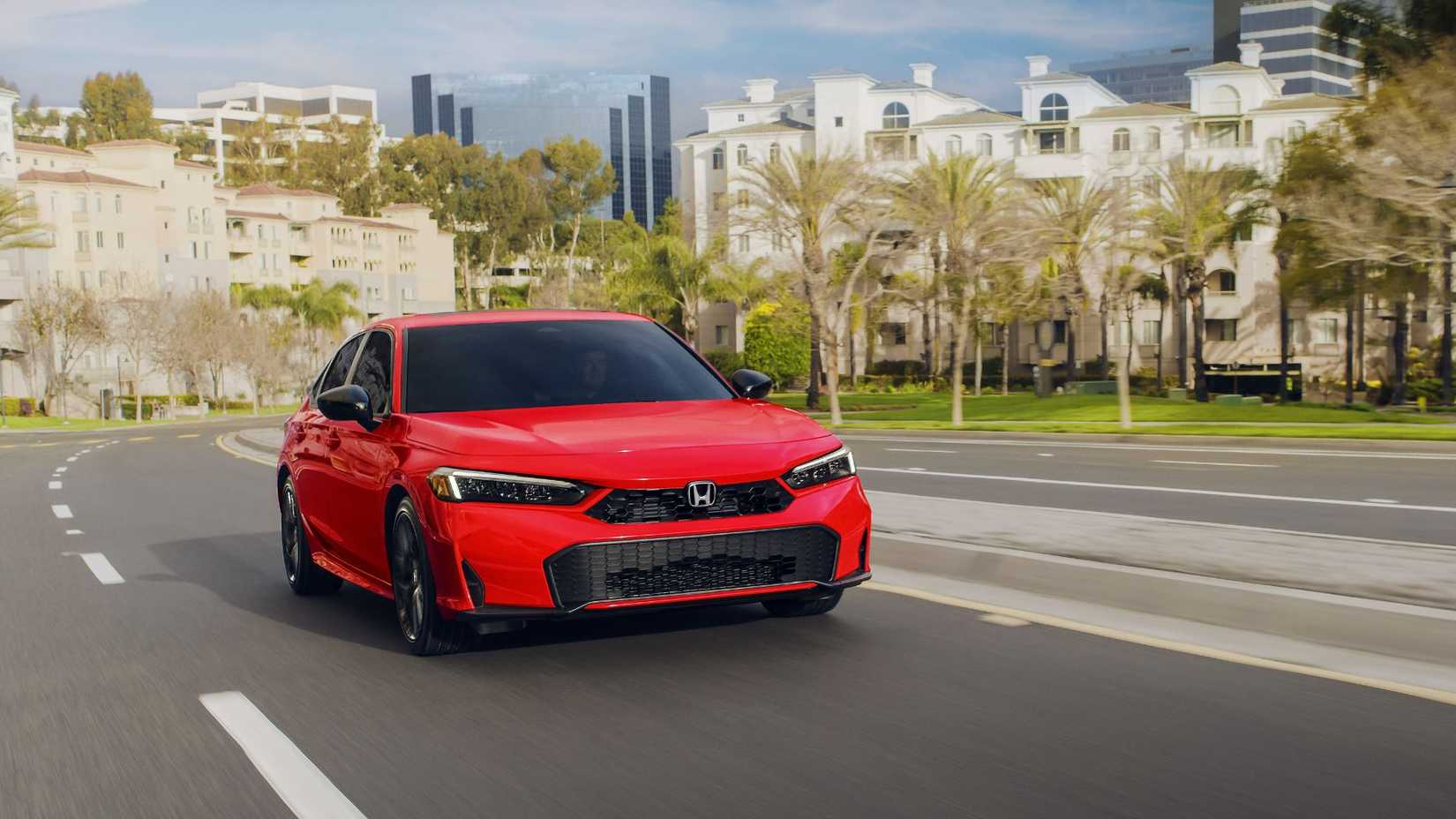 Dynamic Front 3/4 Thot One Red Honda Civic Sedan Sport Hybrid 2025 leading to a city.